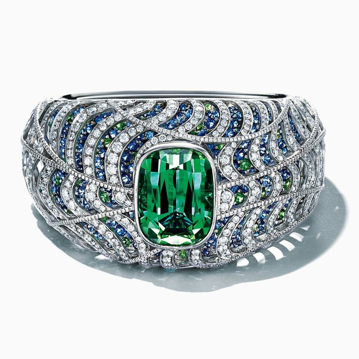 A sea of sapphires, tsavorites and diamonds ebb and flow around a magnificent to...
