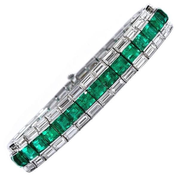 An 18 karat white gold square step-cut Colombian emerald line bracelet with bagu...