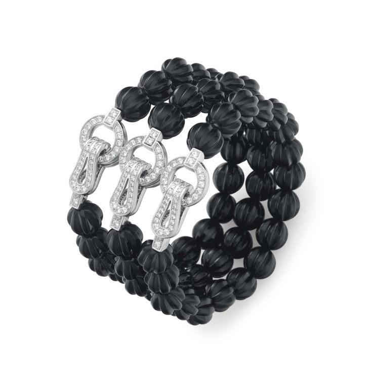 AN ONYX AND DIAMOND BRACELET, BY CARTIER. Designed as three rows of carved onyx ...