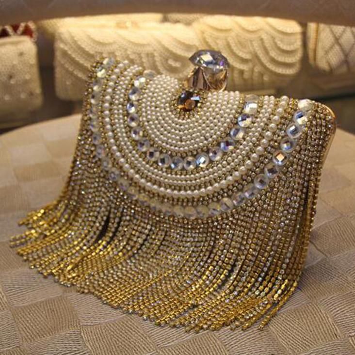 Opulent gold chain tassel clutch with diamonds and pearls decorating the front. ...