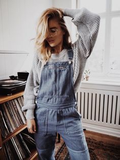 Denim overalls and chunky grey knit sweater.